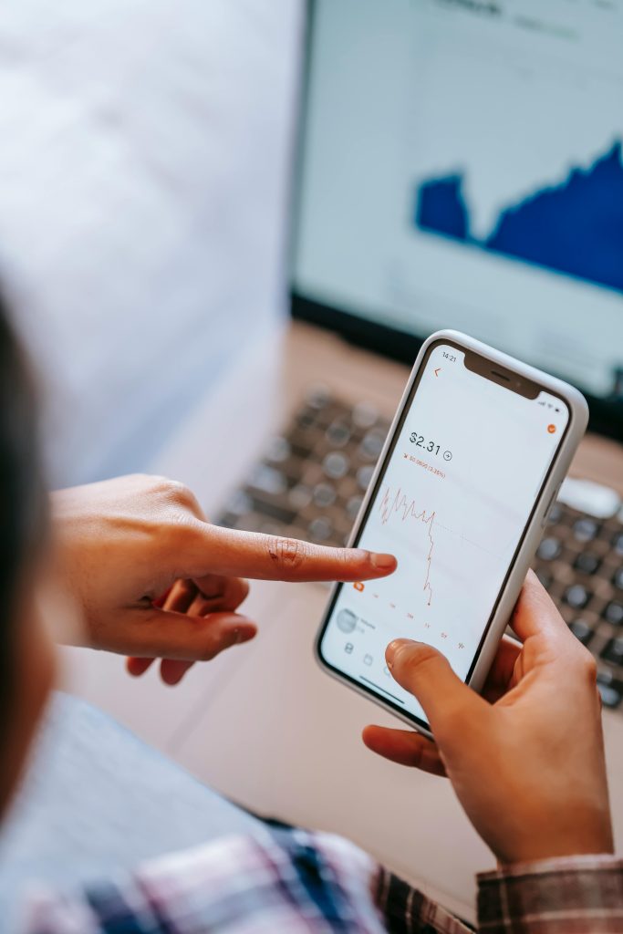 Close-up of hands using smartphone to analyze stock market data.
